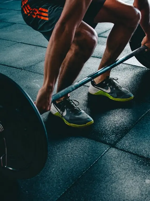 A person lacing up trainers before a workout at the gym